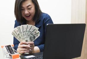 une femme intelligente en vêtements de travail bleus détient plusieurs billets dans ses expressions de joie. concept de vente de marchandises ou de faire des affaires en ligne. photo