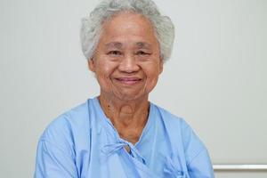 aînée asiatique femme âgée patiente assise et visage souriant avec plaisir sur le lit à l'hôpital. photo