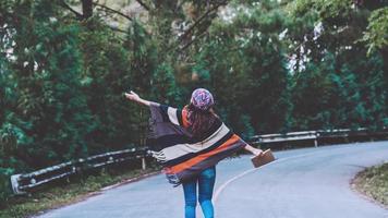 jeune femme voyage nature. elle marche sur une route goudronnée dans le vert des pins forestiers et écrit une note parmi les pins profitant de la nature. photo