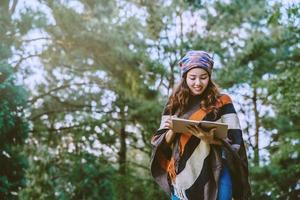 femme asiatique voyage nature. voyager se détendre. étudier lire un livre. éducation à la nature écrivez une note dans un parc public en été. en Thaïlande photo