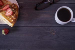 gaufres belges aux fraises et café sur une table en bois sombre. photo