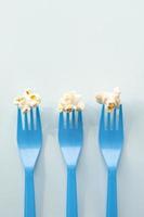 savoureux maïs soufflé salé sur des fourchettes en plastique bleu avec espace de copie pour le texte. concept alimentaire minimaliste. gros plan, vue de dessus et prise de vue en studio. photo