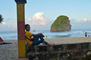 malang, indonésie, 2022 - paysage de plage avec des gens s'appuyant sur la clôture de la plage de la grotte chinoise à malang, java oriental photo