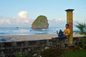 malang, indonésie, 2022 - paysage de plage avec des gens s'appuyant sur la clôture de la plage de la grotte chinoise à malang, java oriental photo