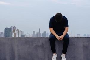 l'homme déprimé misérable asiatique s'assoit seul avec le fond de la ville. concept de dépression et de santé mentale. photo