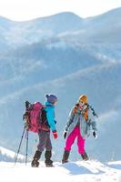 deux femmes sont montées au sommet de la montagne lors d'une randonnée hivernale photo
