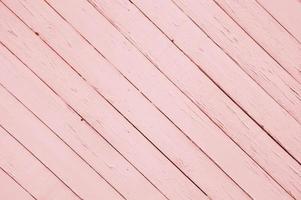 planches peintes en rose. arrière-plan abstrait de vieilles planches de bois placées en diagonale avec une texture de peinture fissurée. photo