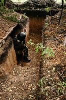 soldat dans une tranchée sur la ligne de front de la guerre ukraino-russe, défense des frontières ukrainiennes contre les orcs. photo