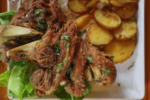 le jarret de porc allemand est servi avec des pommes de terre au four et de la sauce dans une assiette en céramique blanche placée sur la table de la salle à manger pour préparer le jarret de porc pour un festin. photo