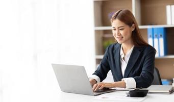 portrait d'une belle femme asiatique d'affaires souriante travaillant au bureau utiliser un ordinateur avec espace de copie. propriétaire d'entreprise personnes PME marketing en ligne indépendant e-commerce télémarketing, concept de travail à domicile photo
