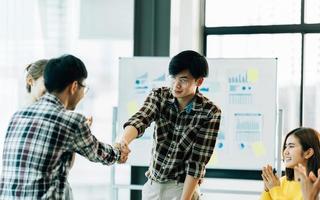 les hommes d'affaires se serrent la main après avoir signé un contrat, tout en se tenant ensemble dans un bureau moderne ensoleillé, en gros plan. concept de communication d'entreprise, de poignée de main et de marketing photo