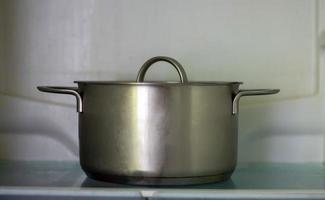 gros plan de pot ouvert de congélateur. casserole dans un réfrigérateur ouvert. le réfrigérateur à l'intérieur est presque vide en raison de la crise économique. ouvrez les étagères du réfrigérateur avec divers aliments cuits. photo