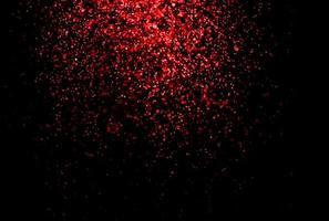 paillettes rouges scintillantes tombant des particules lumineuses sur fond noir pour la célébration, le mariage et la saint valentin photo