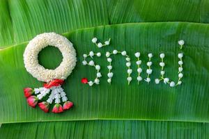 guirlande de jasmin traditionnel thaïlandais. symbole de la fête des mères en thaïlande sur une feuille de bananier avec amour mère en mot thaï. photo