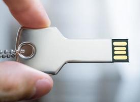 main tenant une clé USB en forme de clé photo