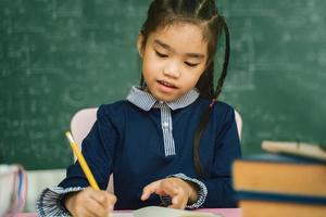 élève du primaire asiatique étudiant ses devoirs en classe. photo