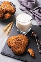 biscuits faits maison céréales avoine et un verre de lait sur la table en béton gris. photo