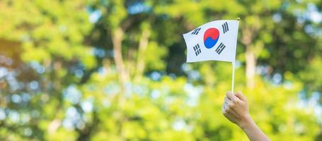 main tenant le drapeau de la corée sur fond de nature. fondation nationale, gaecheonjeol, fête nationale nationale, jour de la libération nationale de la corée et concepts de célébration heureuse photo