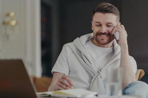 travailleur indépendant souriant parlant au téléphone assis à son bureau au bureau à domicile photo