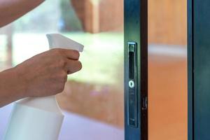 asain maid worker nettoie la porte miroir devant la salle de réunion pour protéger le coronavirus avant le début de l'événement. photo