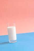 un verre de lait sur fond bleu et rose. photo
