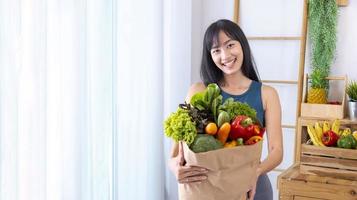 femme japonaise asiatique tenant un sac à provisions du supermarché plein de légumes et de fruits biologiques pour une alimentation saine et une salade végétarienne avec espace de copie photo