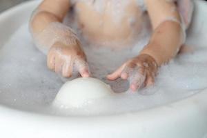 Close up baby girl joue bulle dans l'eau pendant le bain photo