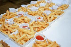 frites dans l'assiette en papier de la rangée sont disposées sur la table prêtes à servir. photo