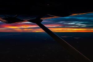 crépuscule à la nuit depuis l'avion à réaction voir le ciel bleu orange rouge avec la lumière de la ville de thaïlande ci-dessous photo