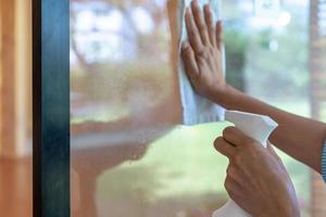 asain maid worker nettoie la porte miroir devant la salle de réunion pour protéger le coronavirus avant le début de l'événement. photo