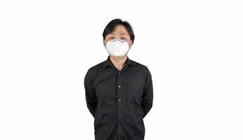 homme moyen asiatique dans une chemise noire, porte un masque n95 blanc, se tient devant un fond blanc clair.