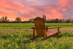 fauteuil en bois à l'extérieur dans les terres agricoles au coucher du soleil photo