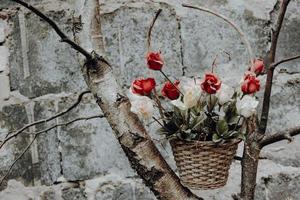 un vieux panier de fleurs avec des roses devant un mur de briques photo