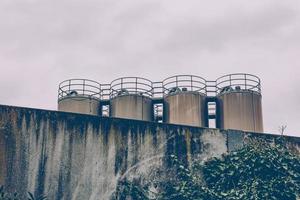 Quatre réservoirs de stockage métalliques industriels au-dessus d'un mur photo