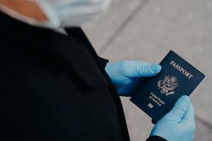 un touriste inconnu porte des gants médicaux en caoutchouc, détient un passeport, ne peut pas voyager pendant la propagation de la maladie pandémique, prévient le coronavirus. impact négatif sur le tourisme mondial. covid 19, danger, virus photo