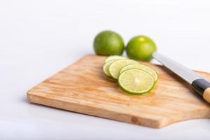 tranches de citron vert et graines avec un couteau placé sur une planche de bois photo