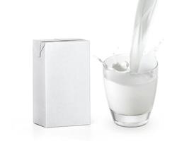 verser un verre de lait créant des éclaboussures et une boîte d'emballage isolée sur fond blanc photo
