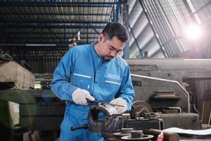 un ingénieur professionnel asiatique de l'industrie travaille dans un uniforme de sécurité avec des outils de précision pour la métallurgie, des tours mécaniques et un atelier de pièces de rechange dans l'usine de fabrication d'acier. photo