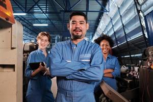 les travailleurs de l'industrie multiraciale en uniformes de sécurité collaborent avec l'unité, les bras croisés et expriment un travail heureux avec le sourire et la joie dans une usine mécanique, profession d'ingénieur professionnel. photo