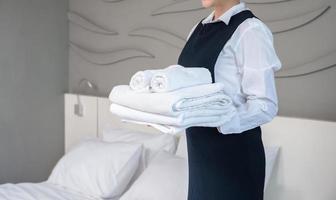 femme de ménage de service en chambre tenant des serviettes blanches pliées propres dans la chambre d'hôtel photo