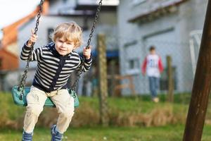 adorable bambin garçon s'amusant balançoire à chaîne sur le terrain de jeu extérieur photo