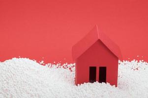 maison de papier dans la neige sur fond rouge