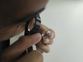 l'homme bijoutier examine le diamant poli à travers la loupe. acheteur vérifiant le diamant. diamant taillé et poli. bijoux en diamants en cours de classement. bijoutier regardant à travers la loupe photo