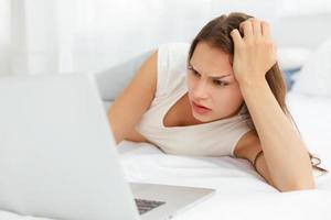 Femme enceinte déprimée travaille à un ordinateur portable en position couchée photo