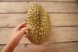 durian, un gros fruit allongé sur un sol en planches brunes. c'est un fruit de thaïlande qui est abondant en été. photo