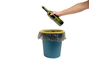 à la main, une bouteille de vin en verre vide est jetée à la poubelle.