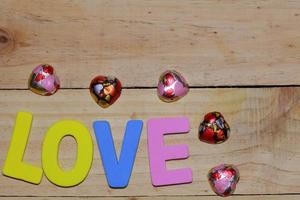 lettres d'amour et coeur en chocolat sur le parquet. fond saint valentin avec des coeurs. concept de la Saint-Valentin. espace pour le texte. photo