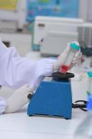 une biochimiste scientifique sur le lieu de travail effectue l'analyse dans le laboratoire moderne. elle tient un compte-gouttes et un tube à essai photo
