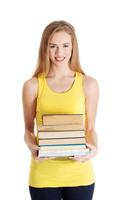 belle étudiante caucasienne décontractée tenant une pile de livres. photo