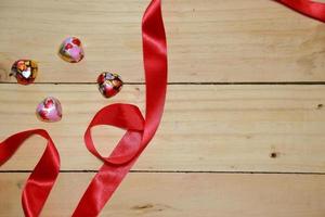concevoir un ruban en forme de coeur rouge et un coeur en chocolat sur un vieux fond de bois vieilli. concept de la Saint-Valentin. espace pour le texte. photo